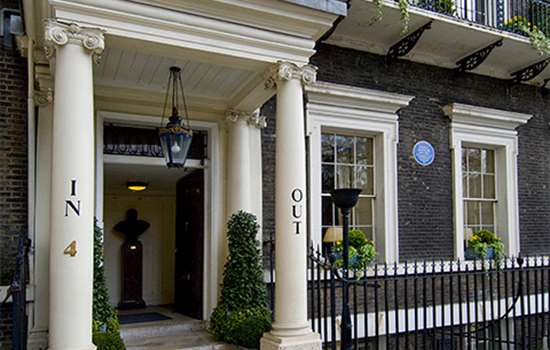 A grand town house with a blue plaque (to Nancy Astor) by the front door