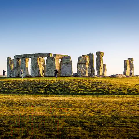 The large stone circle of Stonehenge seen across some grass