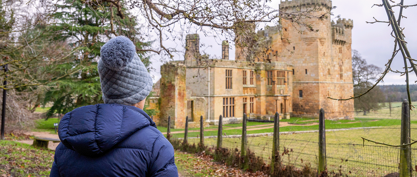 Photo of someone dressed in winter clothing looking across at Belsay Castle in Northumberland